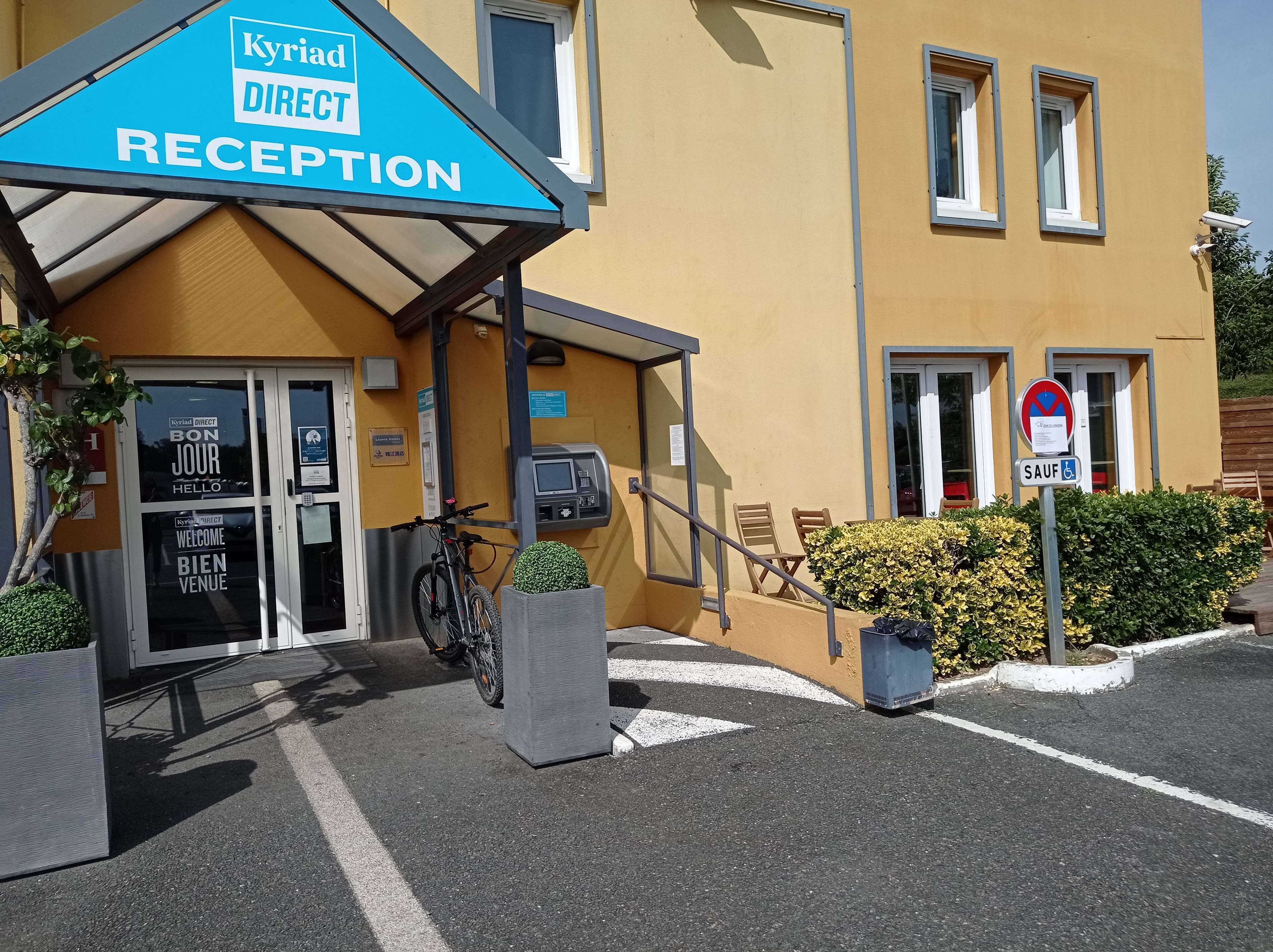 A reception area with a blue sign, a bicycle, and a parking space.