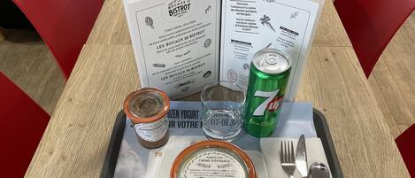 A meal tray with a menu, a 7UP can, a jar of chocolate spread, a glass of water, and a plate with a container of gnocchi cream.