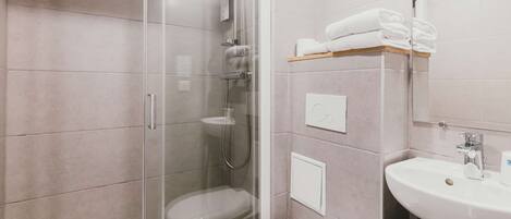 A modern bathroom with a glass-enclosed shower, a white toilet, and a sink with a mirror above it.