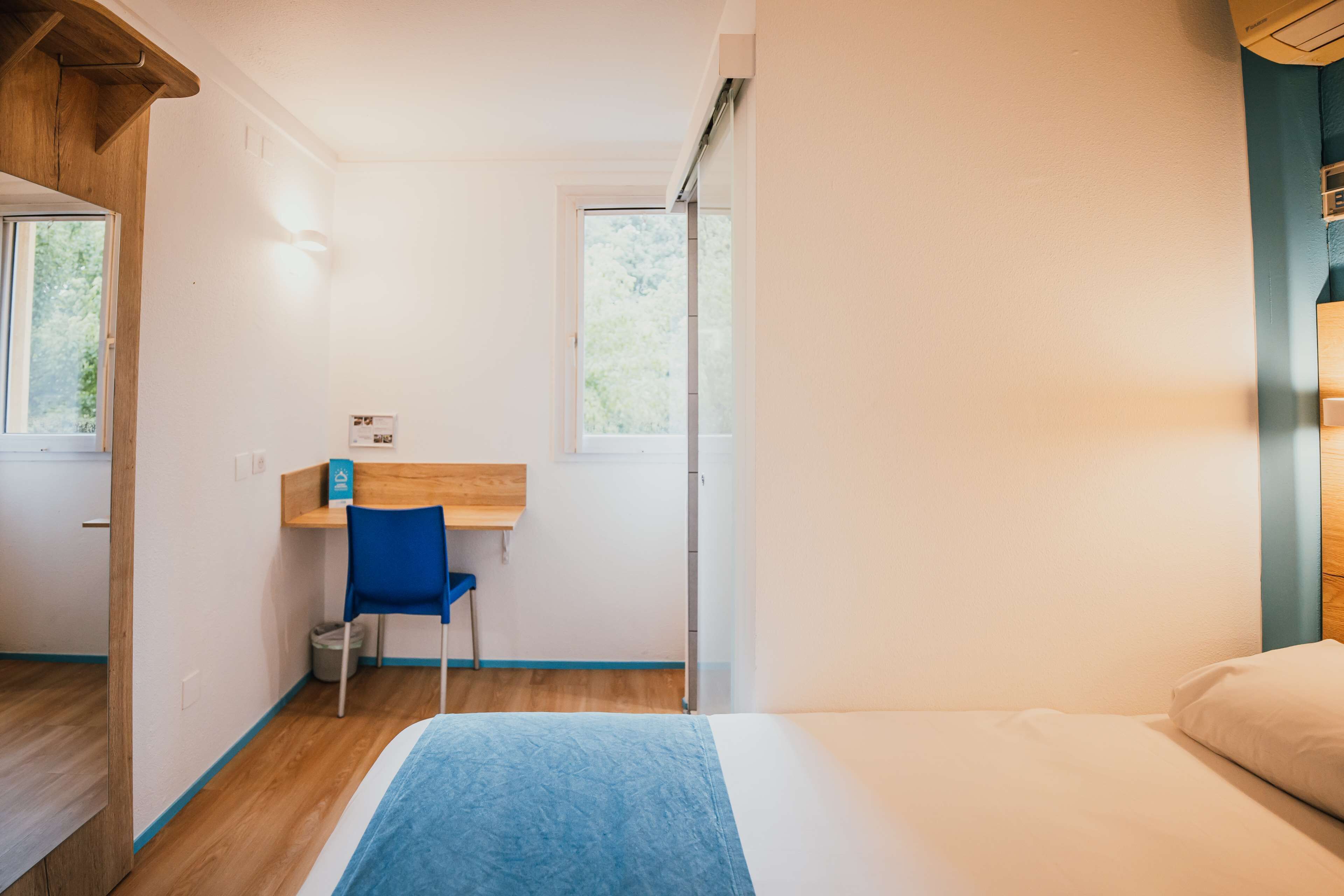 A bedroom with a bed, a desk, and a chair.