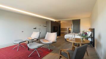 A modern hotel room with a dining area, a kitchen, and a living space.