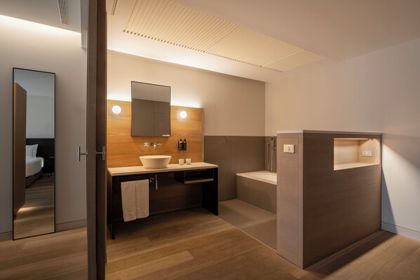 Un baño moderno con tocador de madera, un espejo grande y una zona de ducha separada.