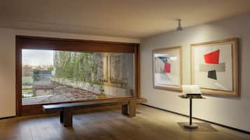 An art gallery with wooden flooring, a bench, and framed artworks on the walls.