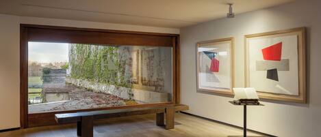 Una galería de arte con suelo de madera, un banco y obras enmarcadas en las paredes.