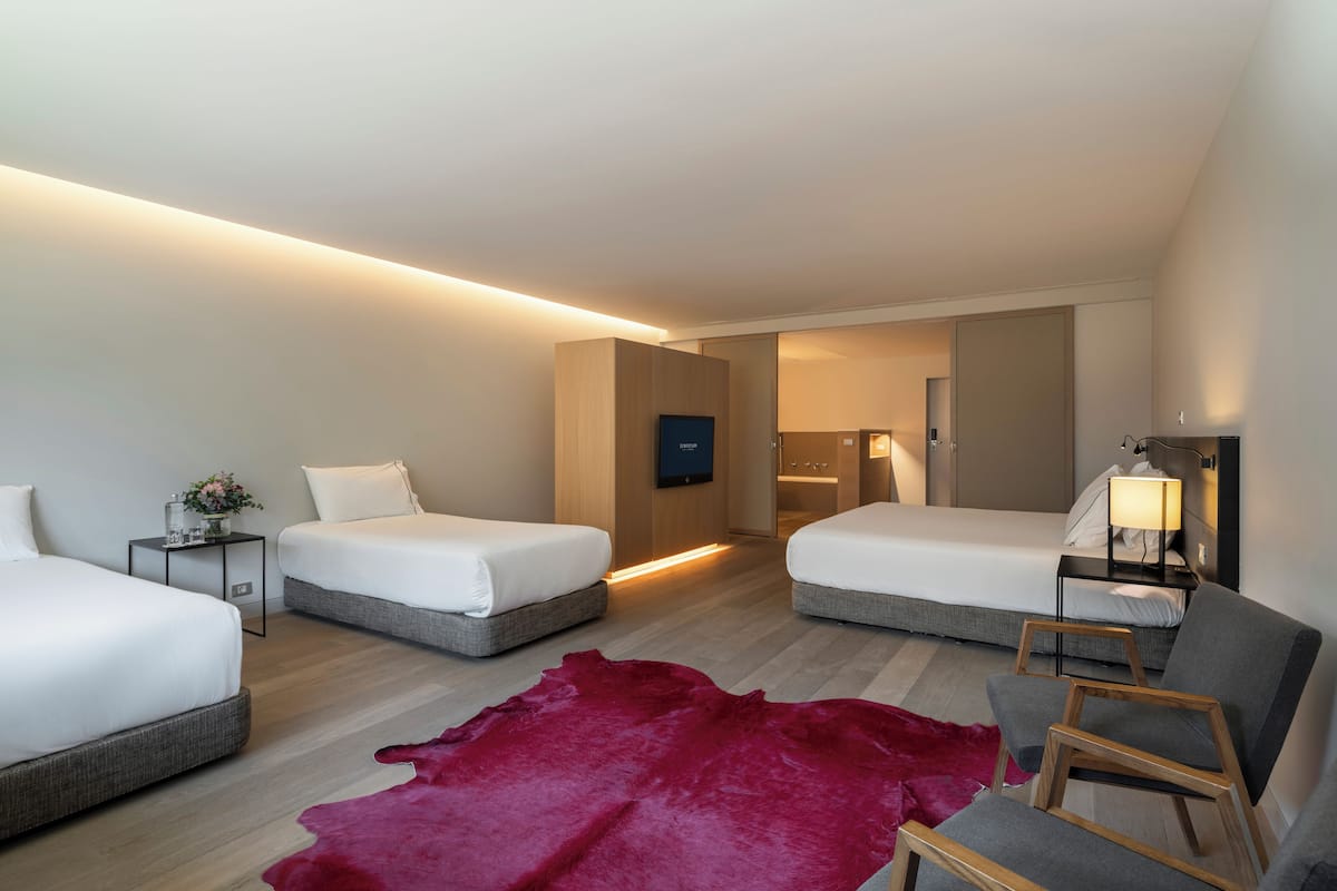 Een moderne hotelkamer met twee bedden, een rood leren vloerkleed en een houten stoel.