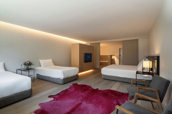 A modern hotel room with two beds, a red leather rug, and a wooden chair.