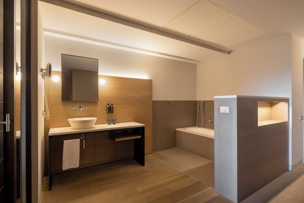 A modern bathroom with a large sink, mirror, and separate shower area.
