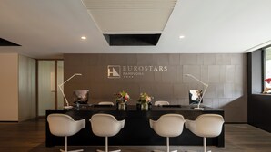 Una zona de recepción con un mostrador negro, sillas blancas y el logotipo de 'Eurostars Pamplona'.
