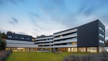A modern multi-story building with a courtyard, large windows, and a flat roof.