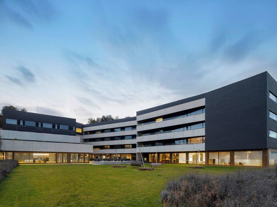 A modern multi-story building with a courtyard, large windows, and a flat roof.