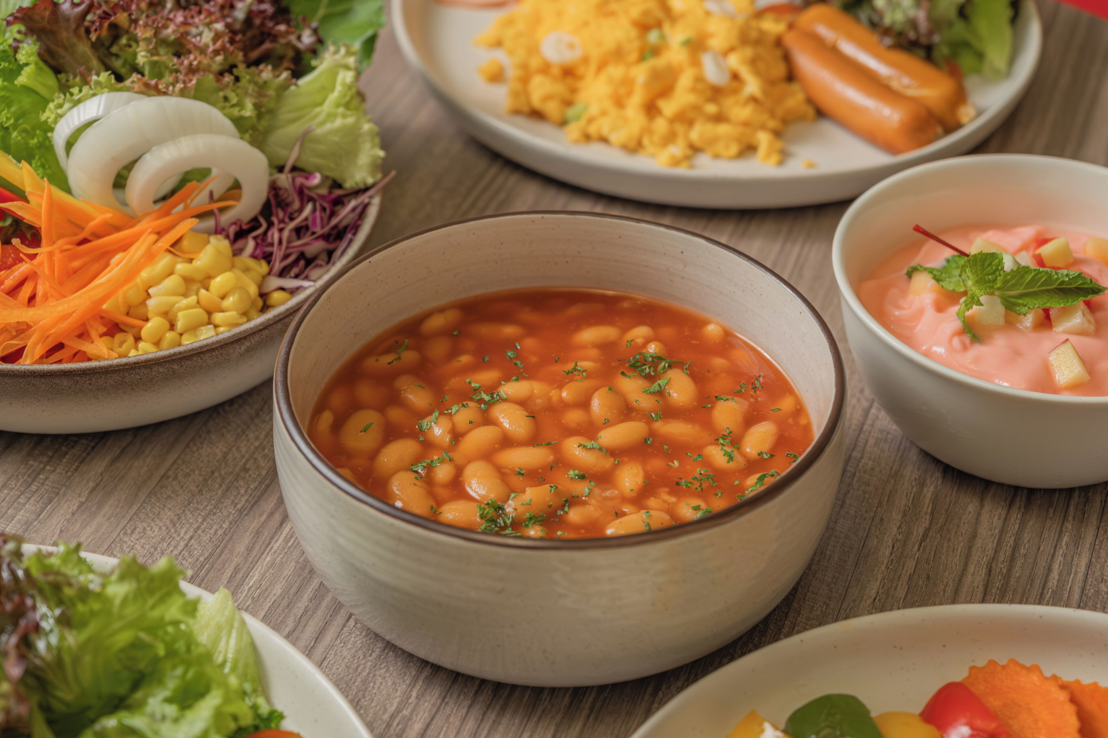 A variety of dishes including beans, salad, and a bowl of soup.