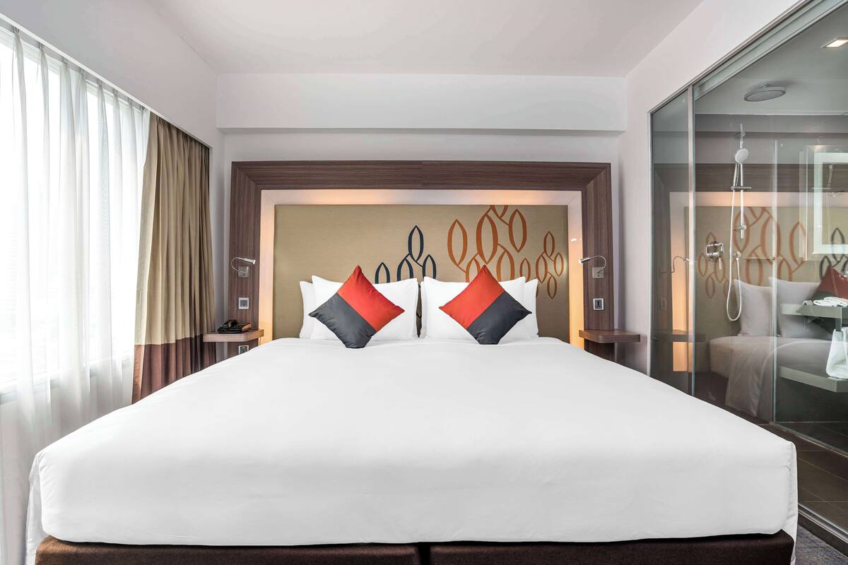 Hotelkamer met een groot bed, een glazen douchecabine en uitzicht op de stad.