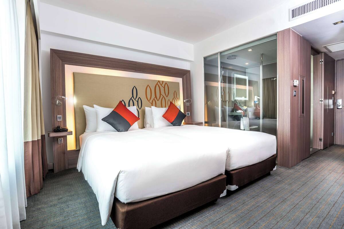 Een hotelkamer met een groot bed, een houten hoofdbord, een nachtkastje en een garderobe.