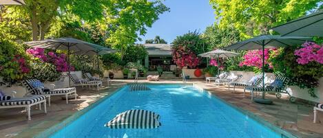 Una piscina al aire libre, sillones reclinables de piscina