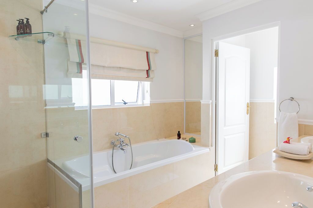 Un baño moderno con cabina de ducha de vidrio, una bañera independiente y un lavamanos amplio.