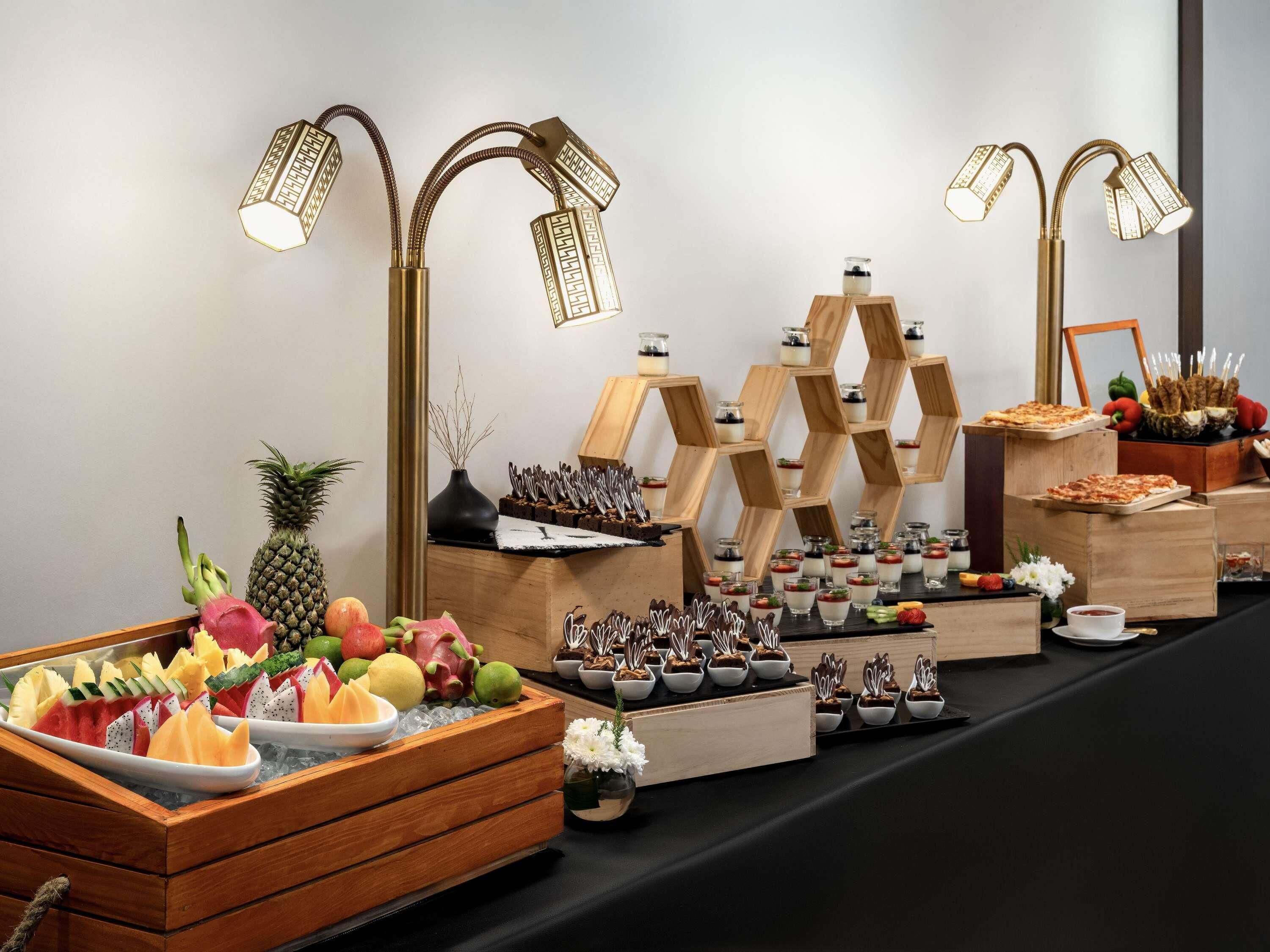 Un bufé con diversas frutas, postres y una decoración central.