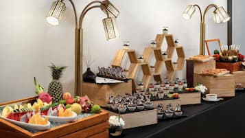 Un bufé con diversas frutas, postres y una decoración central.