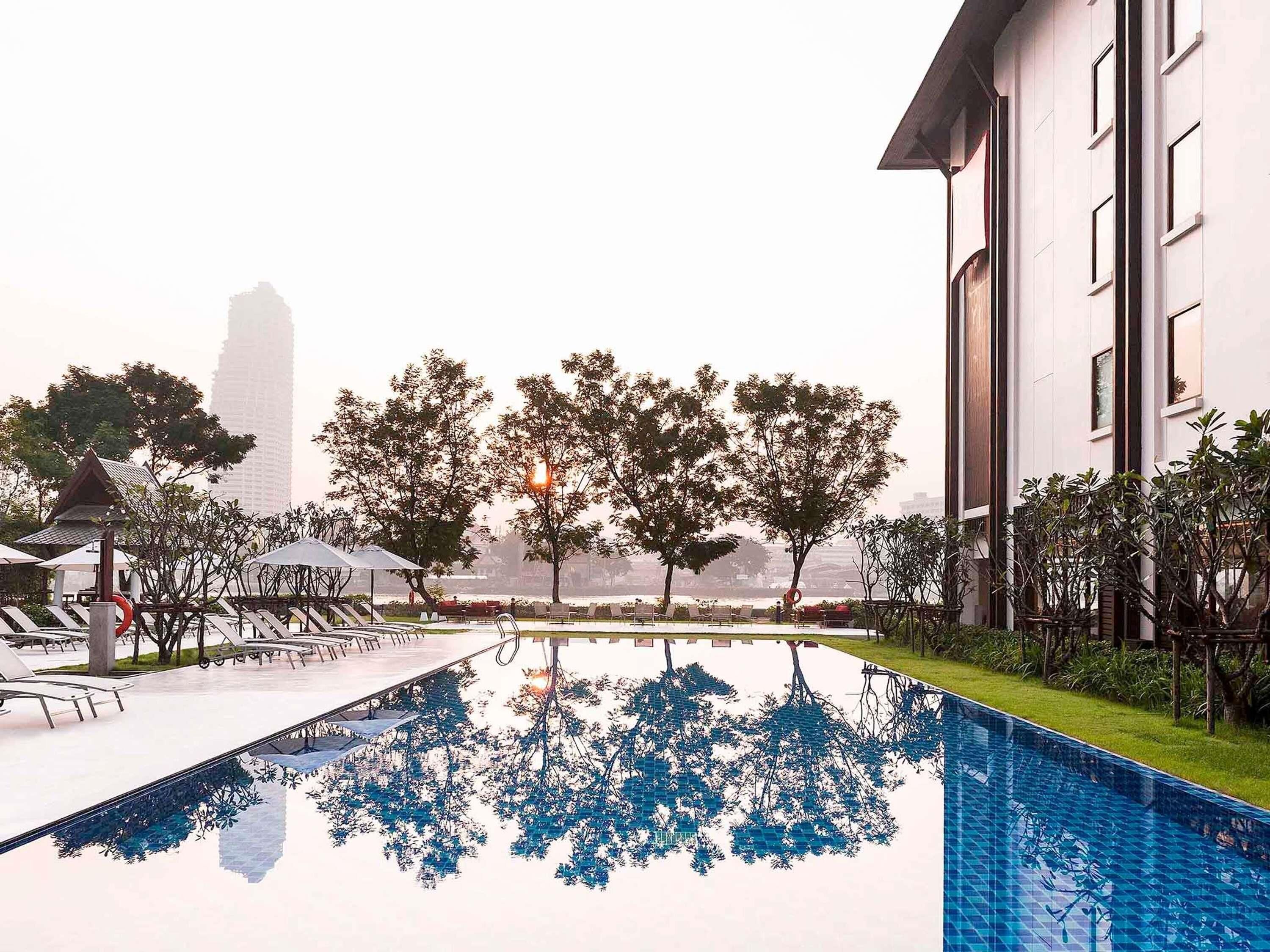 A swimming pool with a clear view of trees and a modern building in the background.