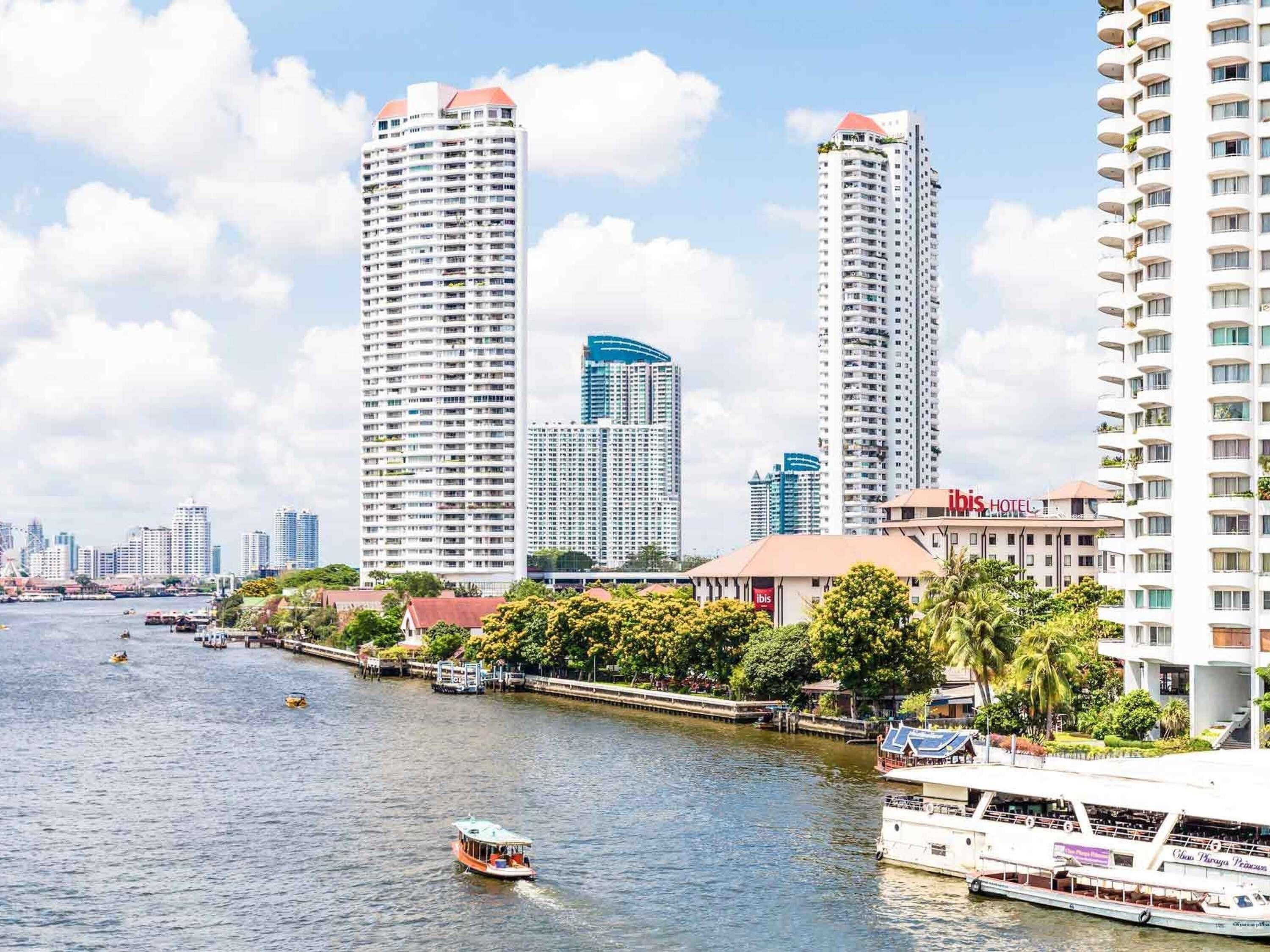 A river with boats, tall buildings, and a hotel named ibis.