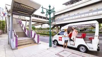 Un fourgon blanc arborant le logo « ibis » était stationné à un arrêt de bus, à côté d’un escalier menant à un bâtiment portant l’inscription « Krung Thon Buri ».