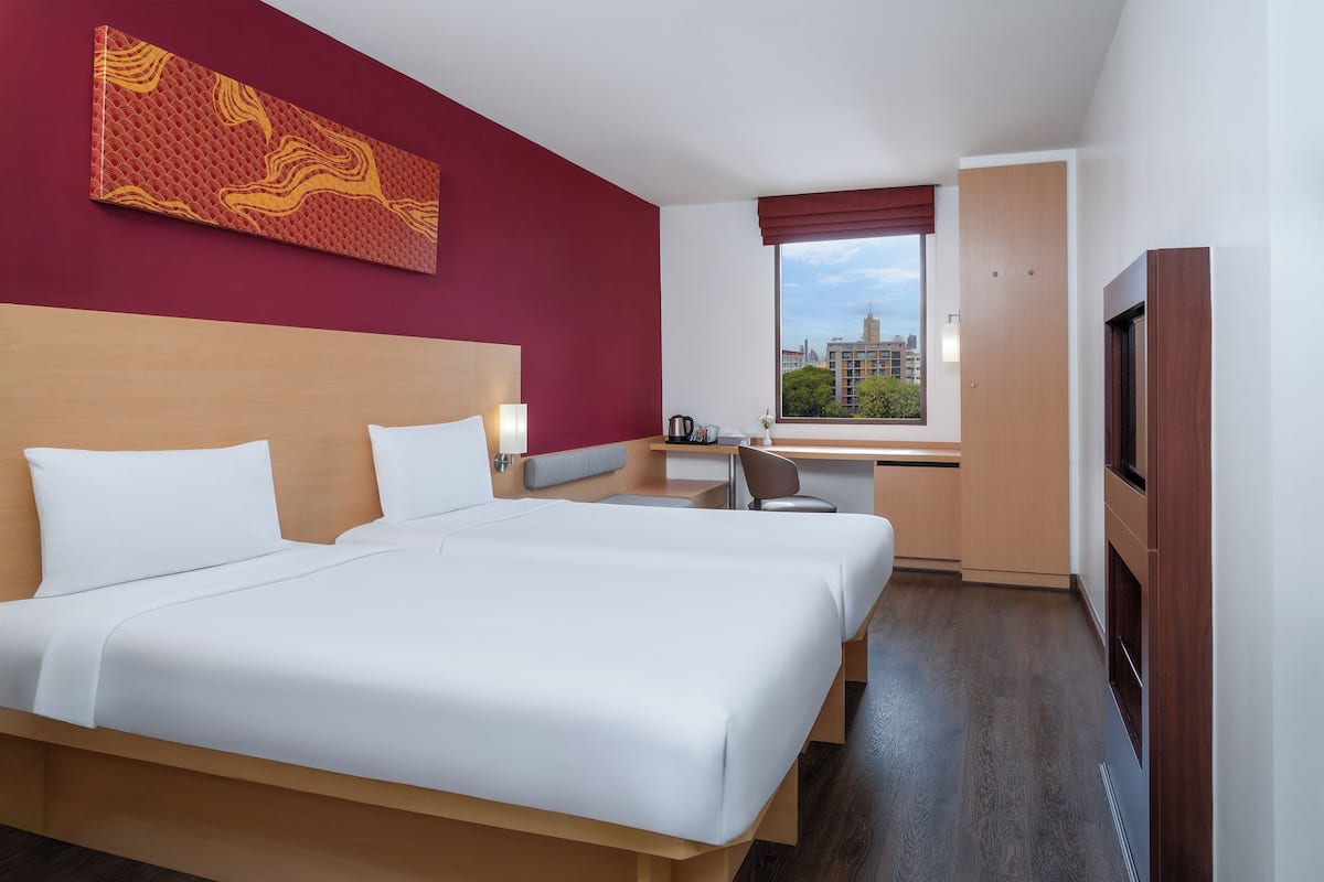 A hotel room with a large bed, a desk, a chair, and a TV.