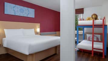 A hotel room with a bed, a bunk bed, a wall art piece, and a window with a view.