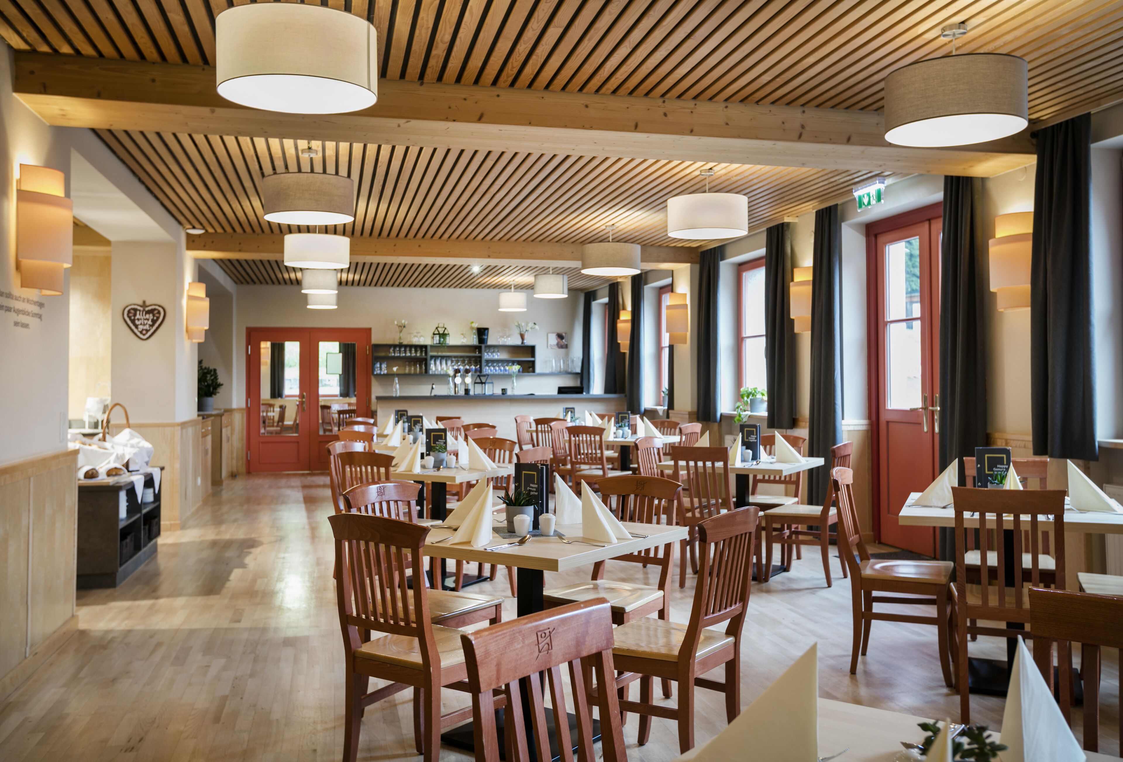 Un restaurante con vigas de madera en el techo, varias mesas y sillas.