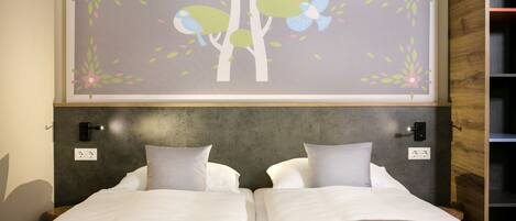 Un dormitorio con una cama, dos mesitas de noche, un cabecero y una obra de arte en la pared de pájaros y árboles.