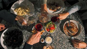 Un grupo de personas reunidas alrededor de una mesa con varios platos y copas de vino.