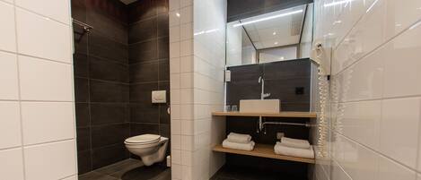 A modern bathroom with a toilet, a shower, and a sink area.