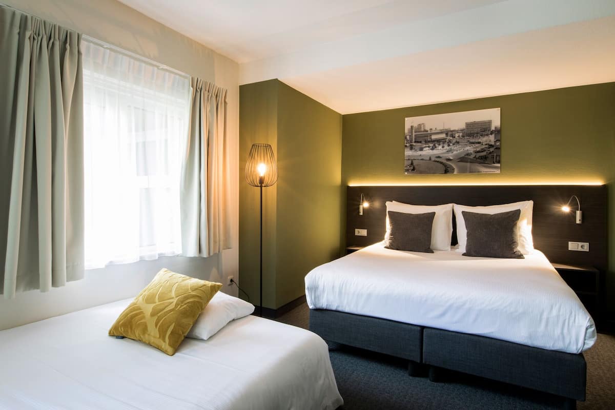 Habitación de hotel con cama, mesita de noche, lámpara y un cuadro colgado en la pared.