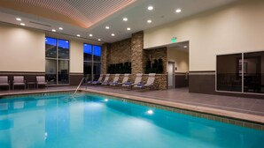 A hotel pool area with lounge chairs, a stone wall, and a view of the outside. - Embassy Suites by Hilton Denver Downtown Convention Center (Denver)
