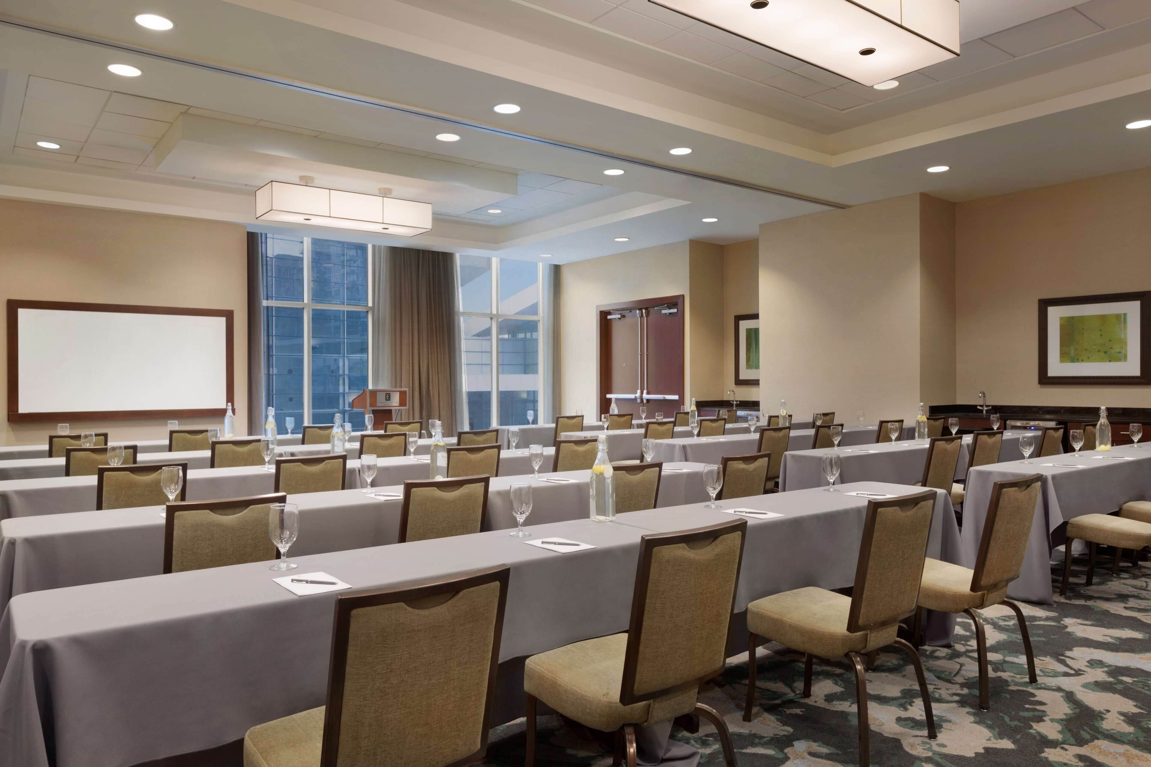 A conference room with long tables, chairs, and a projector screen.