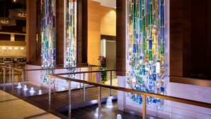 A modern hotel lobby with a glass art installation, a wooden staircase, and a reception area with a counter and chairs. - Embassy Suites by Hilton Denver Downtown Convention Center (Denver)
