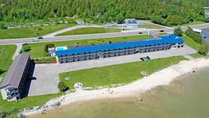 Vue aérienne d’un hôtel, avec un long bâtiment, un parking et une zone de plage.