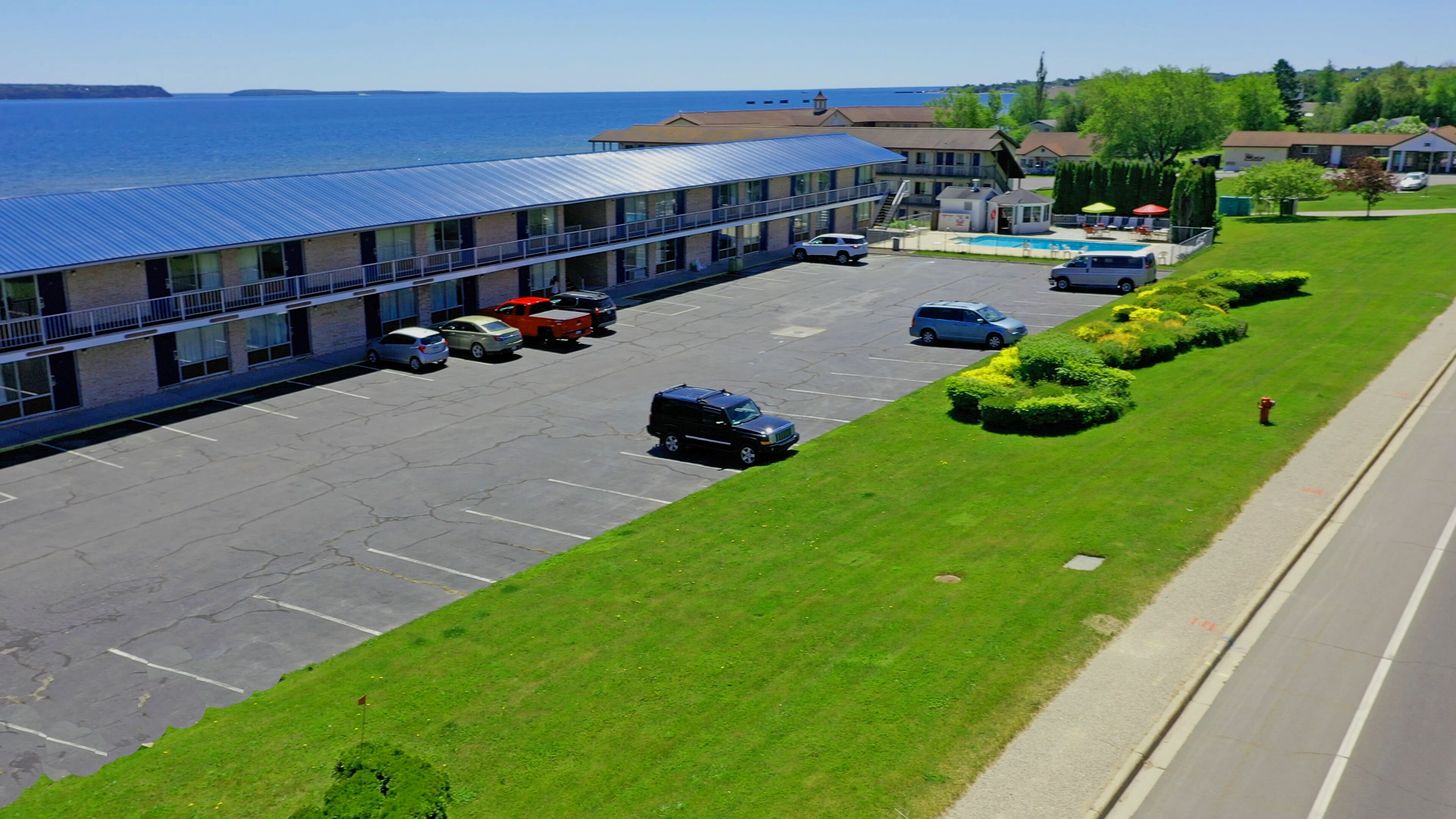 A hotel with a parking lot, a swimming pool, and a view of the sea.