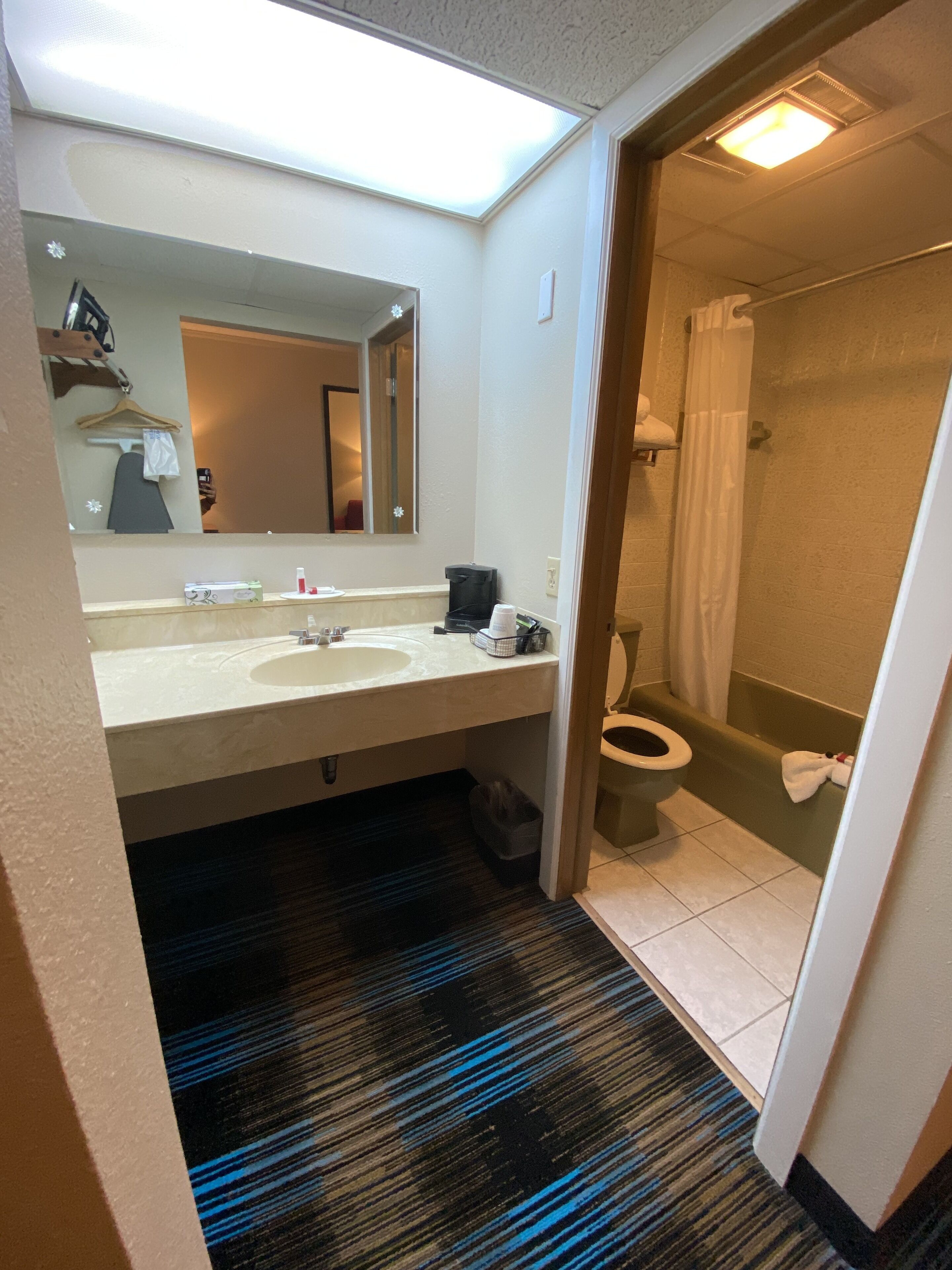 Een hotelbadkamer met een grote spiegel, twee wasbakken, een toilet en een douche.