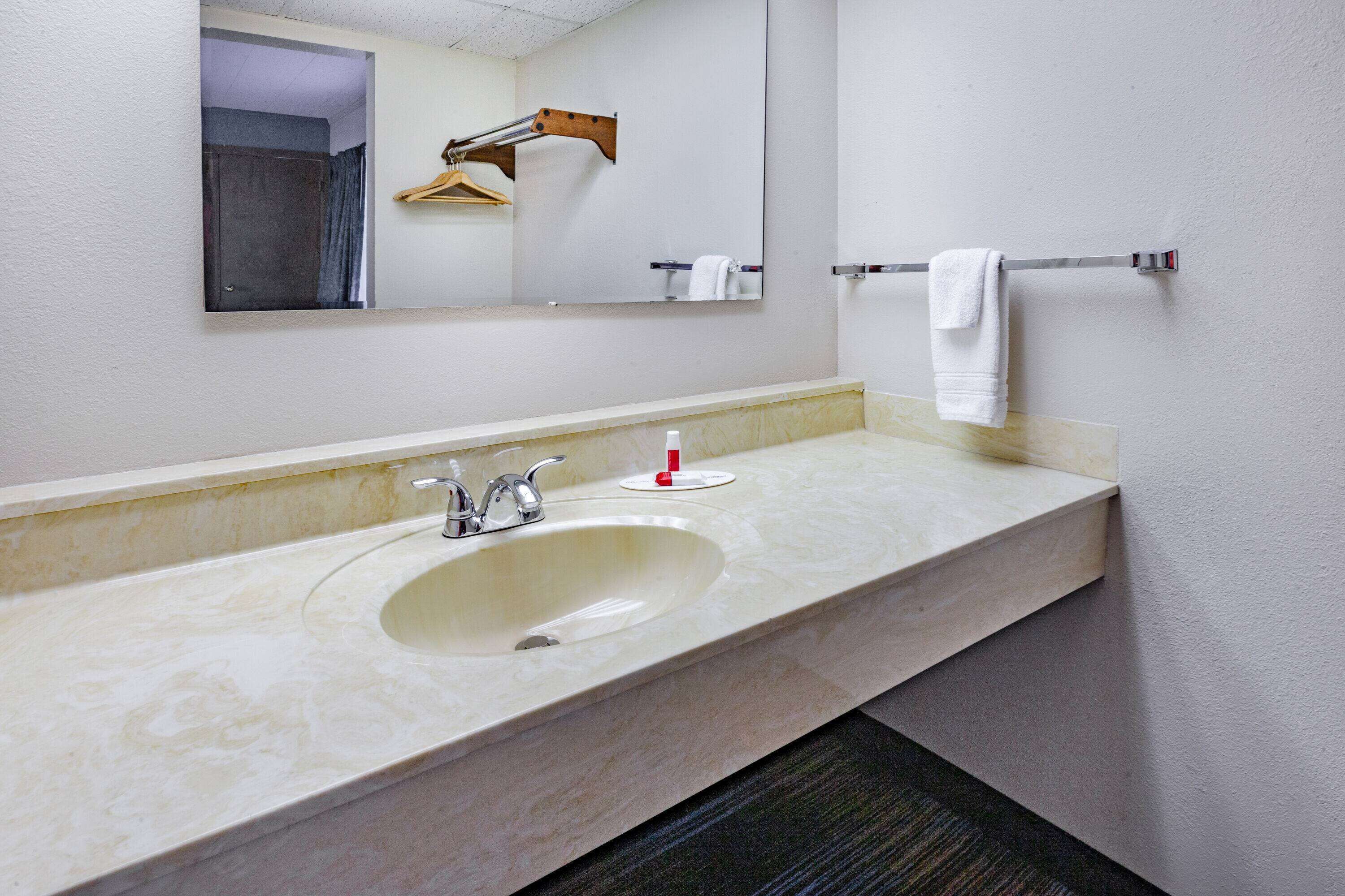 A bathroom with a sink, mirror, towel rack, and a hanging towel.