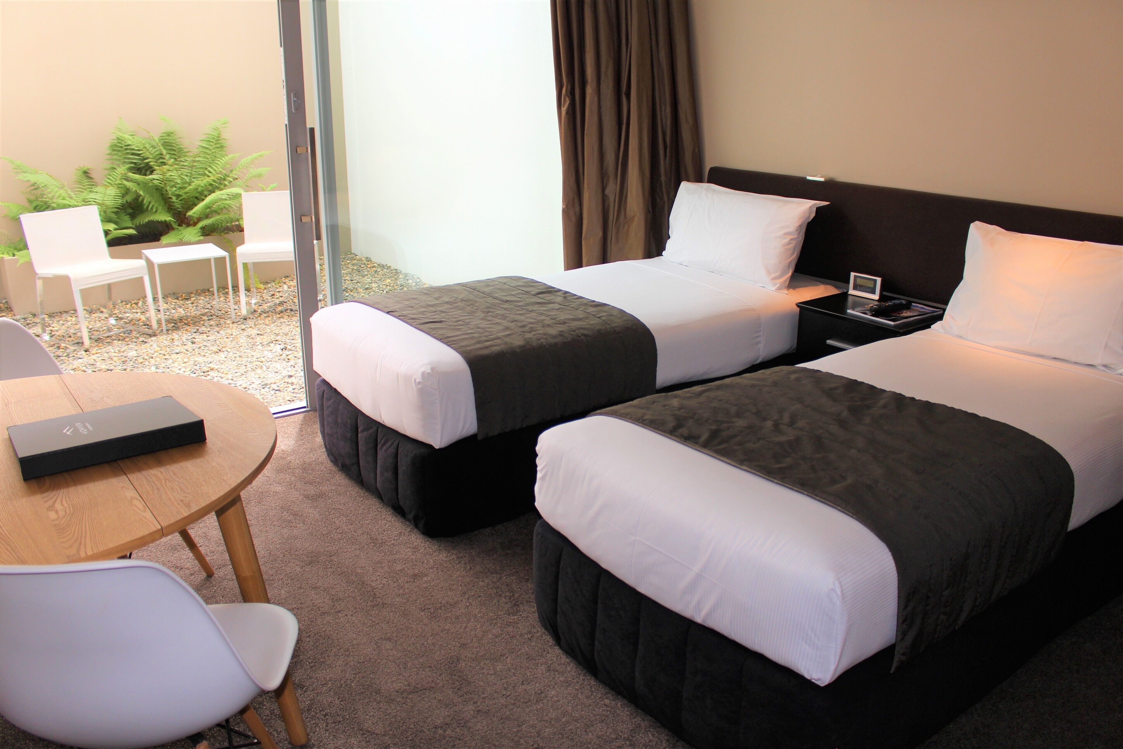 Una habitación de hotel con dos camas, una mesita y dos sillas.