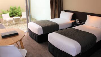 Una habitación de hotel con dos camas, una mesita y dos sillas.