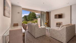 Ein modernes Wohnzimmer mit einem Glastisch, zwei Sofas, einem Kamin und Bergblick.