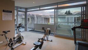 Ein Fitnessstudio mit Cardiogeräten, großen Fenstern und Bergblick.
