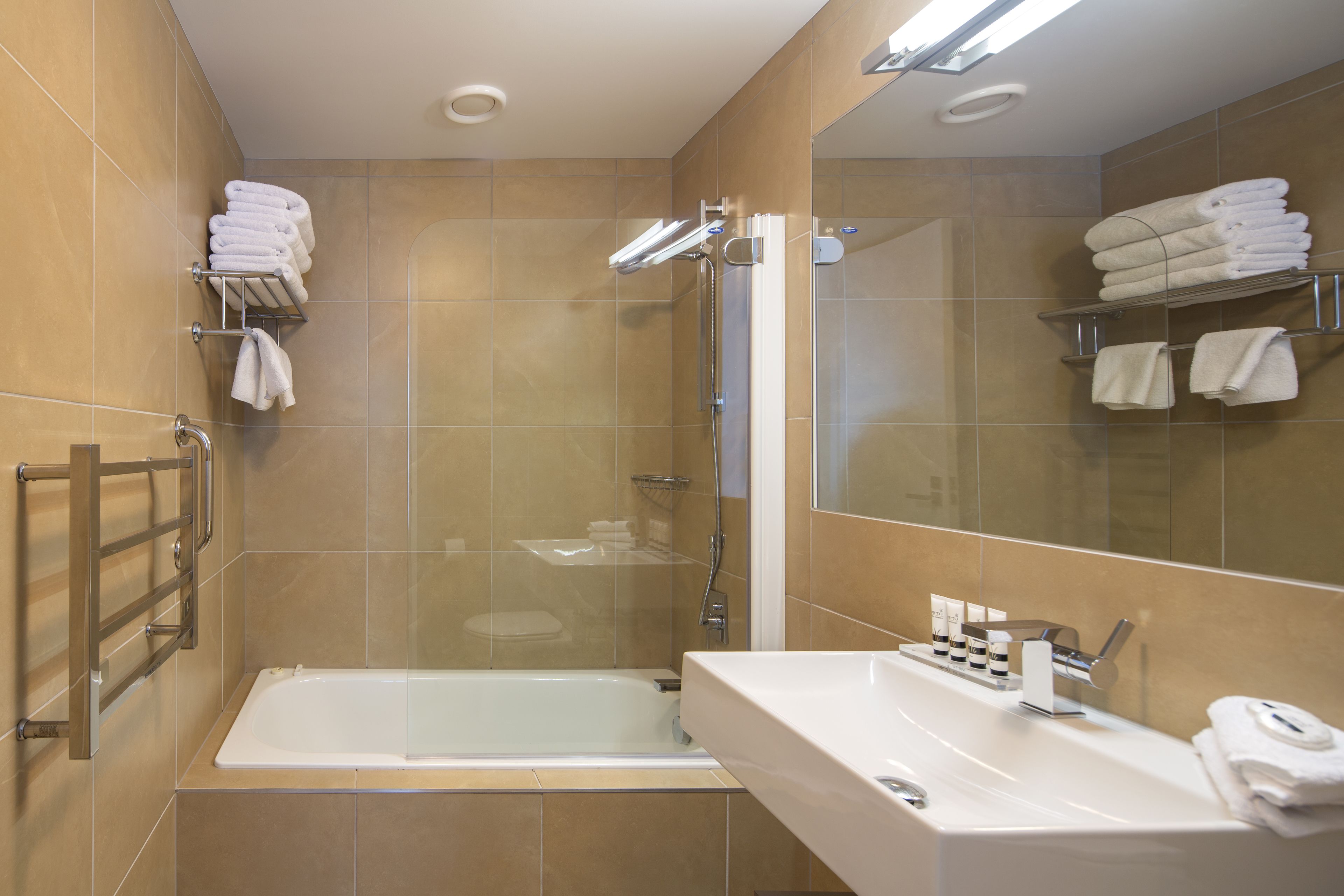 Un bagno moderno con una vasca, un lavandino e una doccia. Ci sono portasci sulle pareti e uno specchio sopra il lavandino.