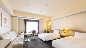Una habitación de hotel con dos camas, un sofá, una mesita y una silla.