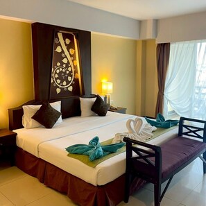 Une chambre d’hôtel comprenant un lit, une table de chevet, une lampe, une fenêtre avec des rideaux et un élément de décoration murale.