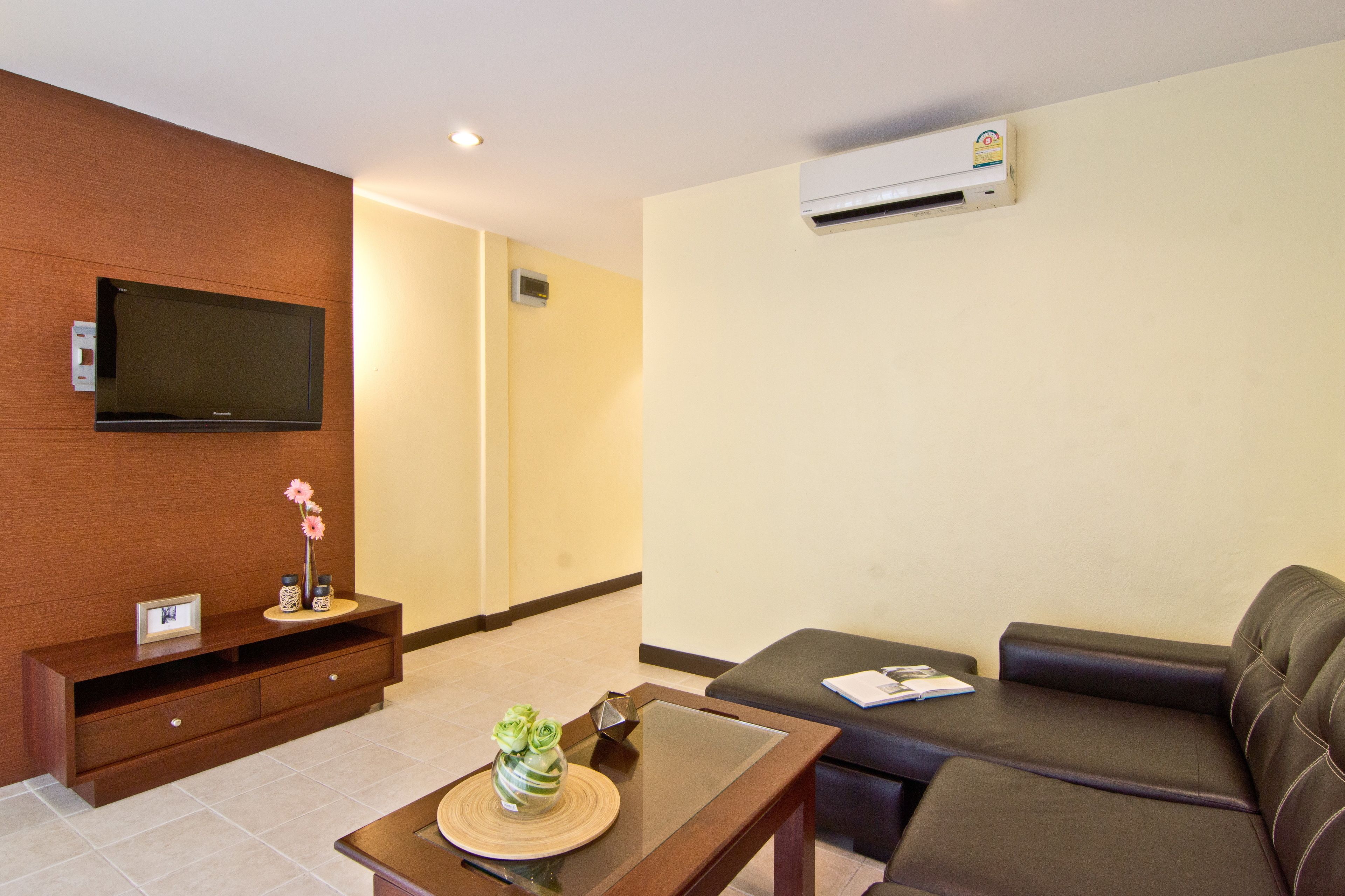 A modern living room with a flat-screen TV, a sofa, a coffee table, and a wooden console with decorative items.