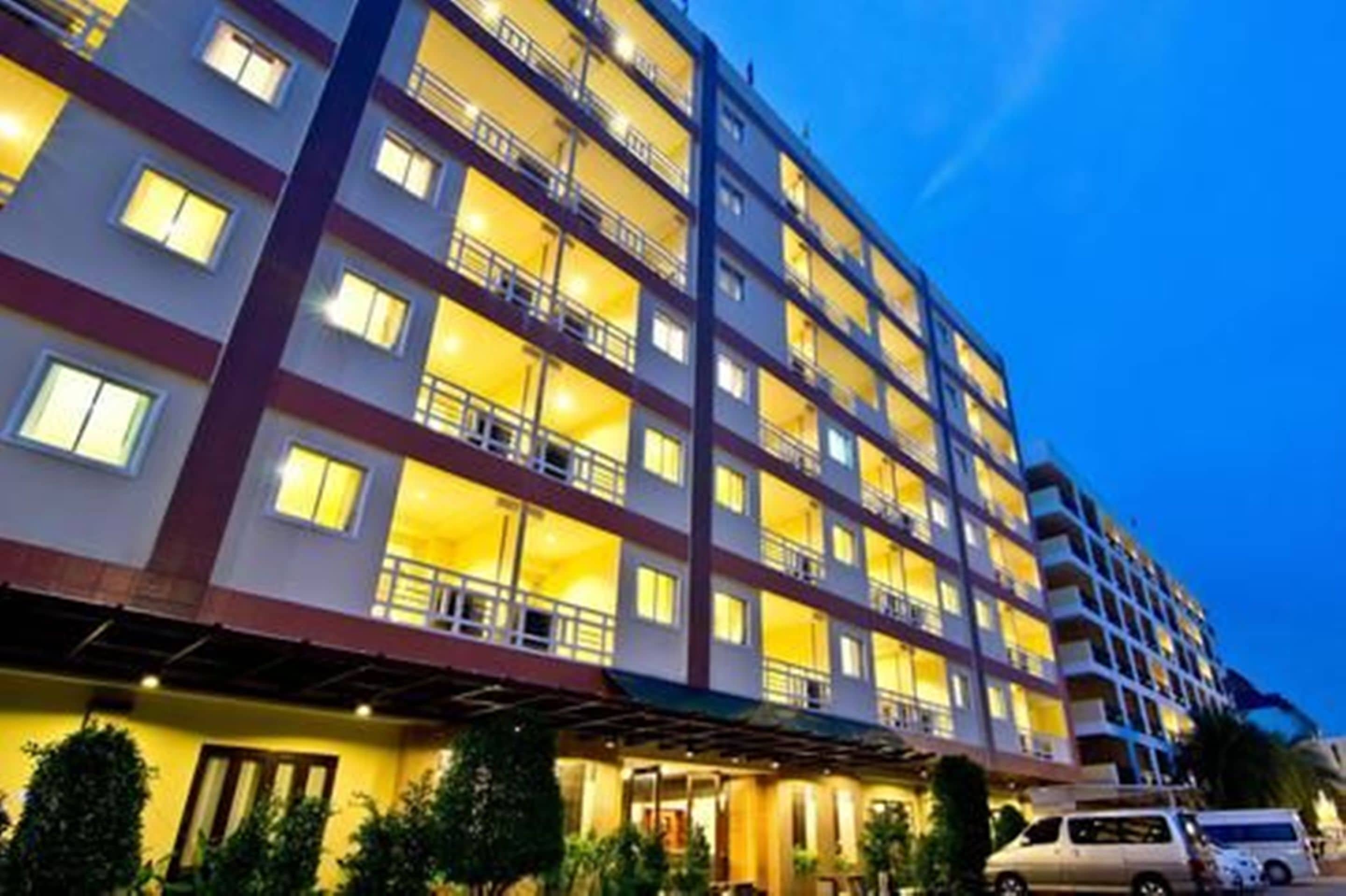 A multi-story hotel with balconies and a well-lit entrance.