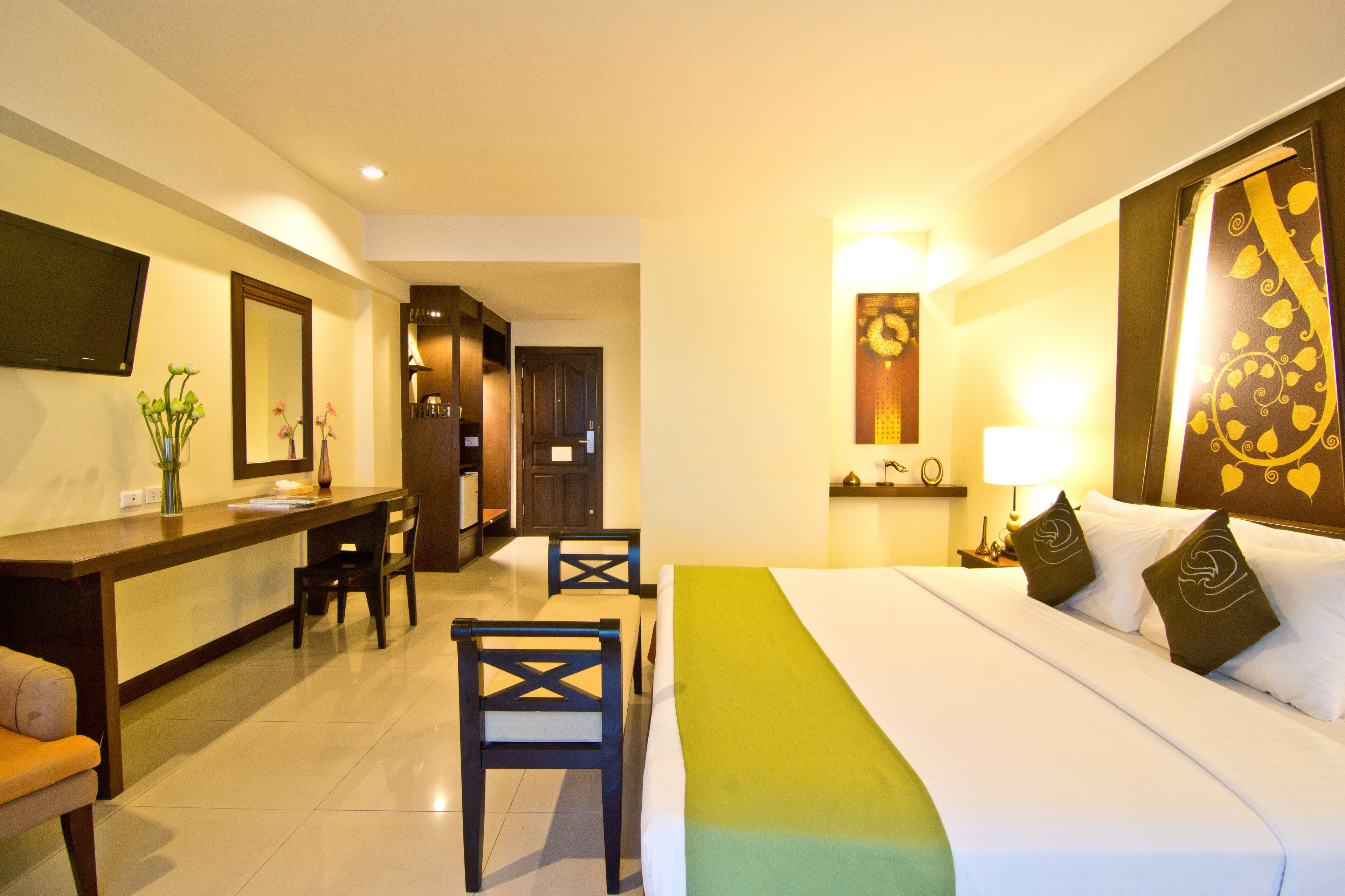 A hotel room with a bed, a desk, and chairs.