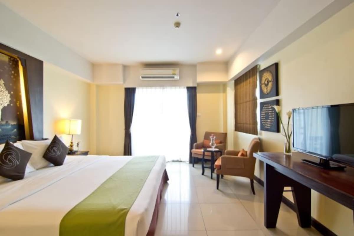 Une chambre d’hôtel avec un lit, un bureau, une chaise et un téléviseur.