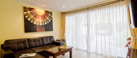 A living room with a brown leather sofa, a wooden coffee table, and a large abstract painting on the wall.